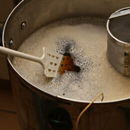 Brewing beer in a large stainless steel pot.
