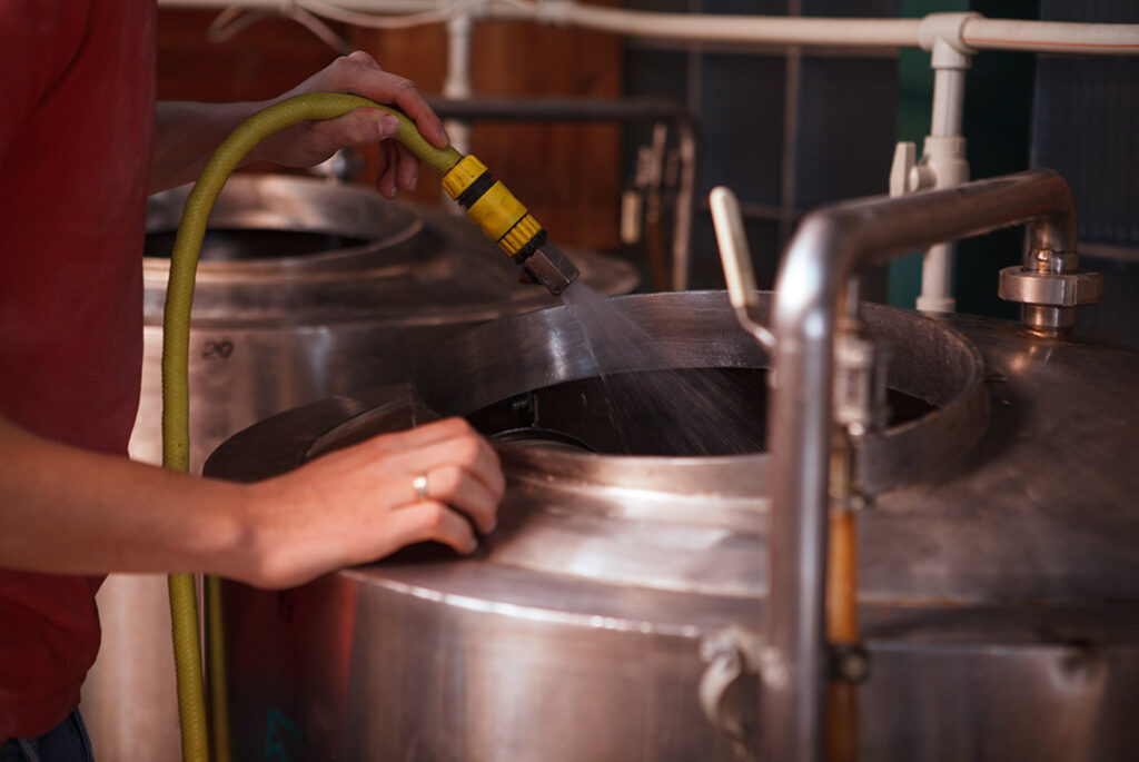 A technician cleaning brewery equipment.